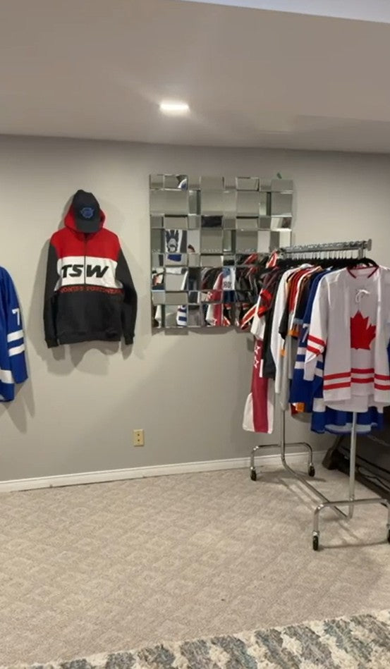 Toronto Sportswear showroom with a custom TSW hoodie and a rack of sublimated hockey jerseys