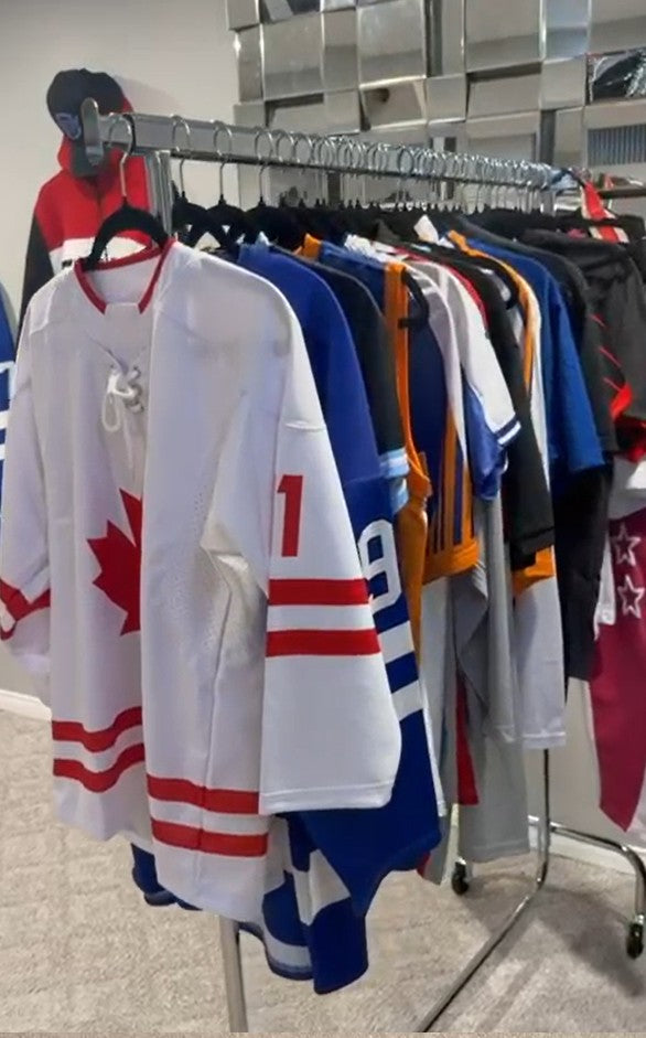Rack of custom sublimated hockey jerseys in red, white, blue and orange
