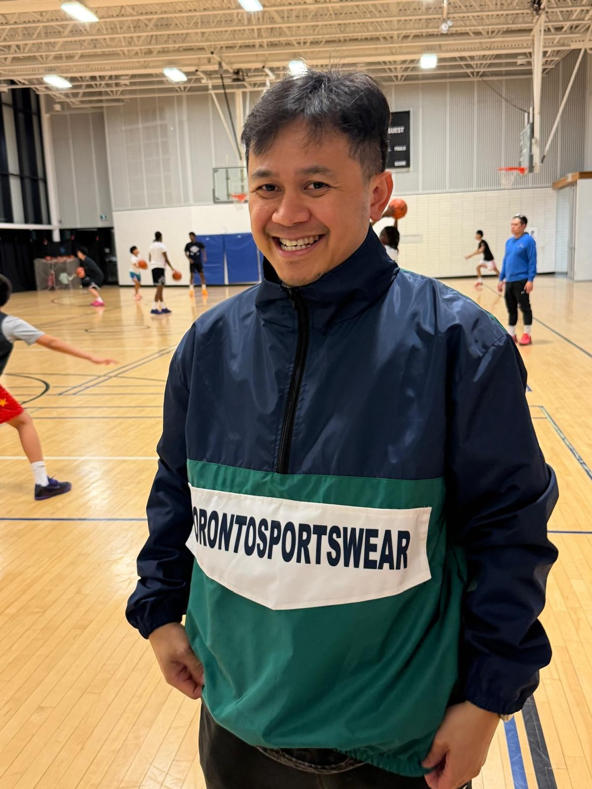 Customer wearing a custom Toronto Sportswear half-zip team jacket in navy, green and white
